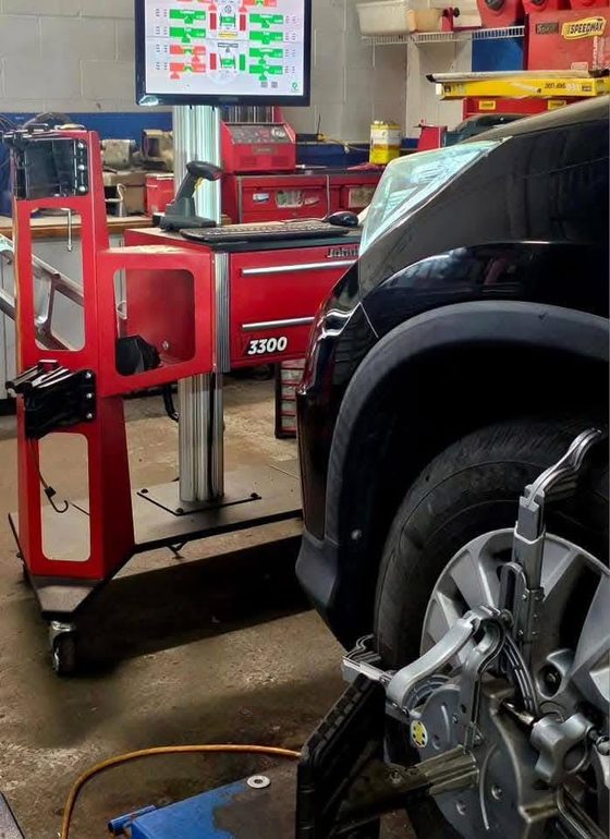 An alignment head clamped to a wheel on the alignment rack at DAVID's Auto Care