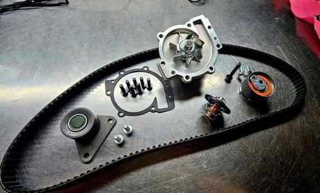 A timing belt kit laid out with the water pump, tensioners and thermostat